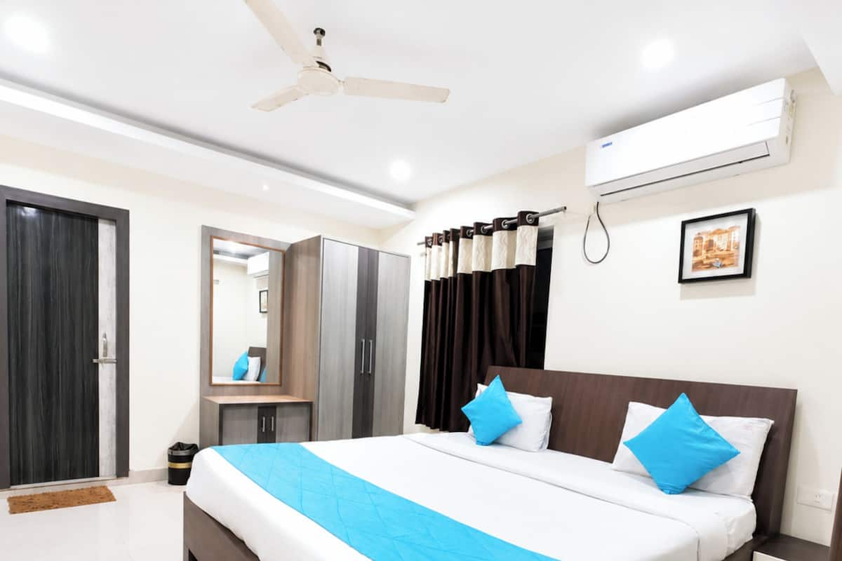 A modern bedroom with a large bed, a ceiling fan, an air conditioning unit, a mirror, and a framed picture on the wall.