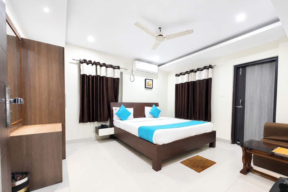A modern hotel room with a large bed, a ceiling fan, a desk, and a wardrobe.