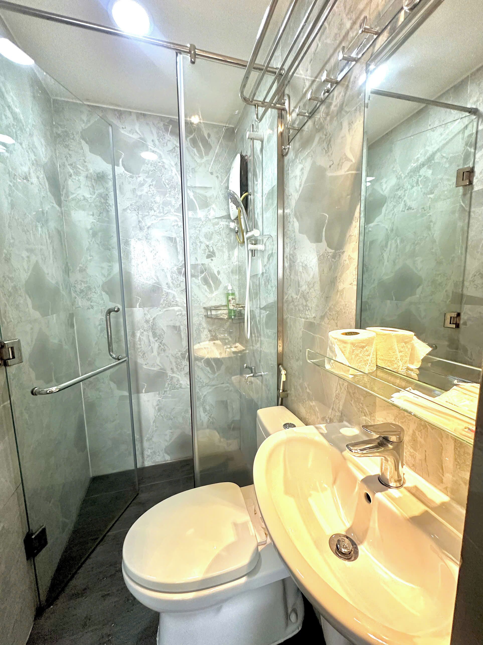 A bathroom with a glass-enclosed shower, a toilet, and a sink.