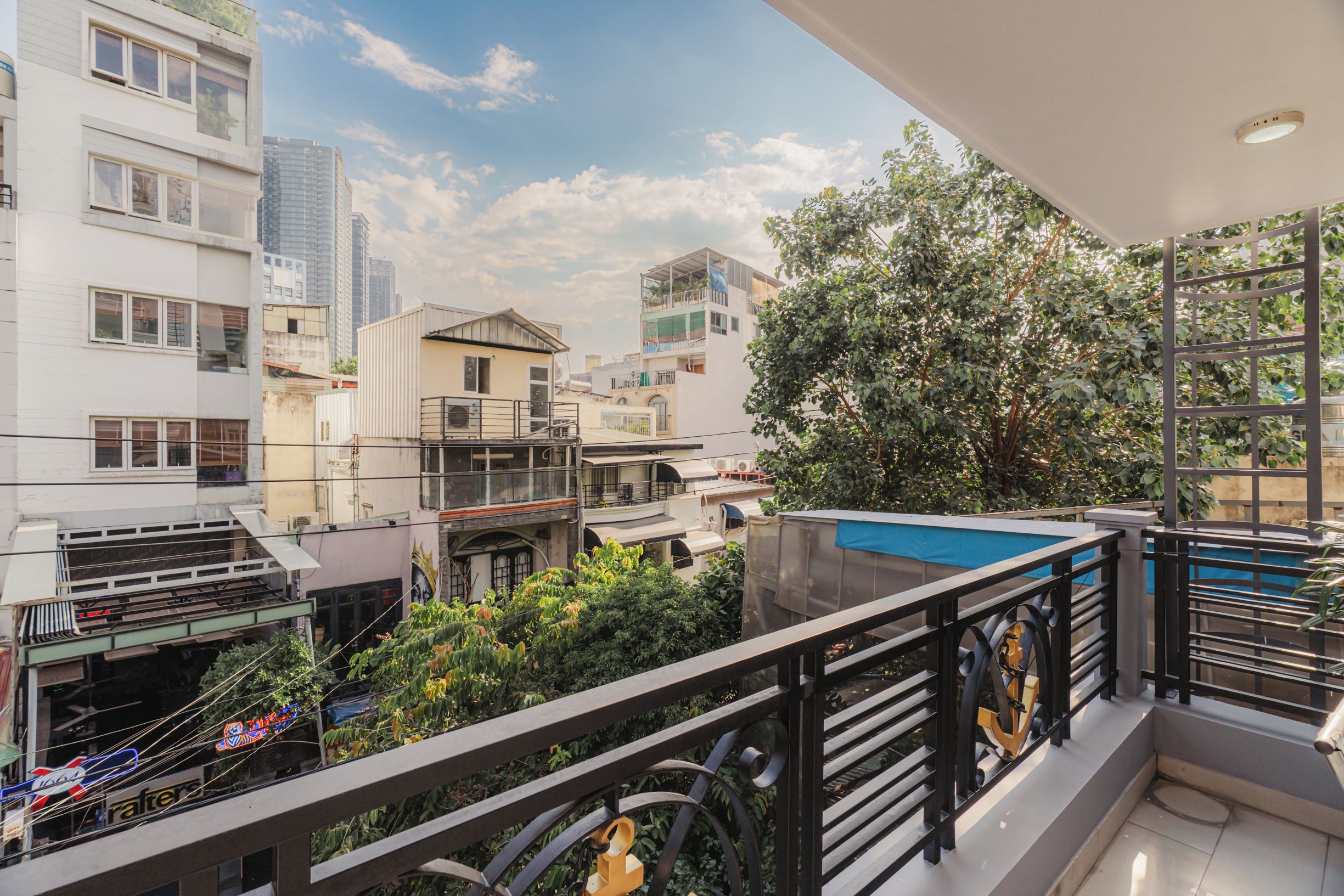 A residential balcony with a view of surrounding buildings and a tree.