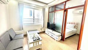 Uma sala de estar moderna com sofá, mesa de centro, TV e cama com cabeceira.