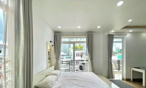 Ein Schlafzimmer mit einem Bett, einem Fenster mit Vorhängen, einem Balkon und einer Deckenleuchte.