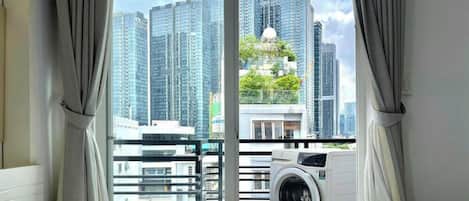 Ein Hotelzimmer mit großem Fenster, einer Waschmaschine und einem Bett.