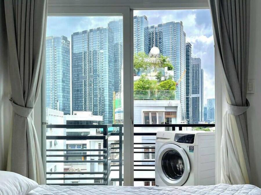 A hotel room with a large window, a washing machine, and a bed.