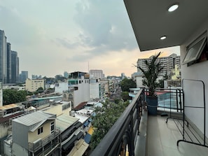 Ein Balkon mit Blick auf eine Stadtlandschaft, darunter Gebäude und ein klarer Himmel.