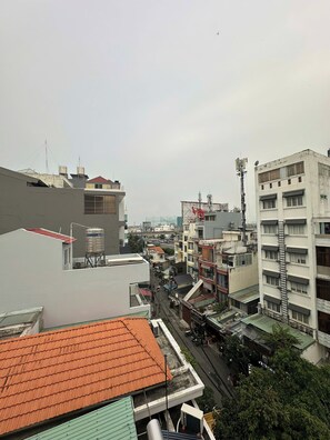 Un edificio de varios pisos con techo plano, tanques de agua visibles y una calle debajo.