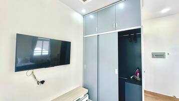 A room with a flat-screen TV mounted on the wall, a built-in bench, and a wardrobe with sliding doors.