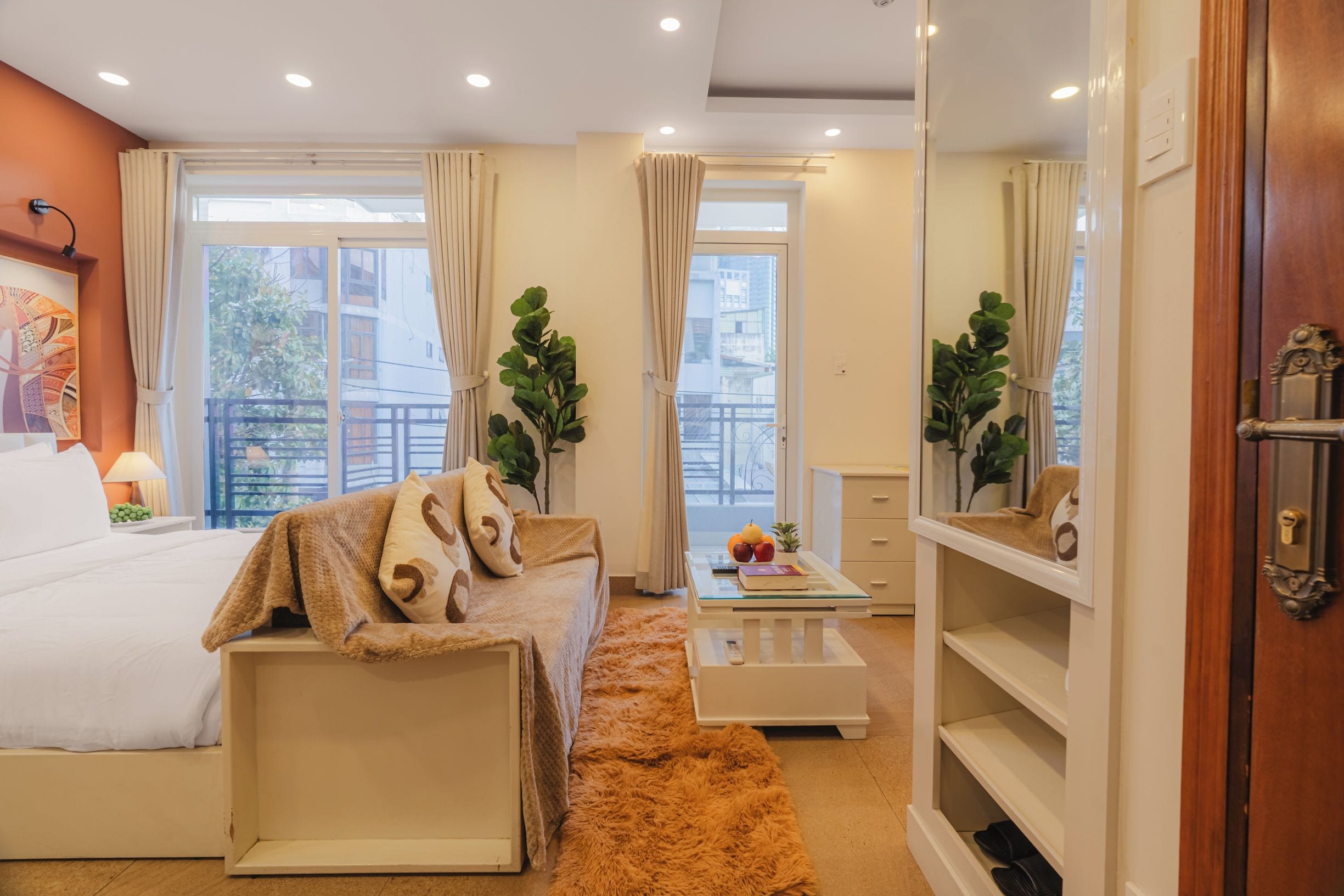 Ein Hotelzimmer mit einem Bett, einer Couch, einem Couchtisch, einem Spiegel und Blick auf die Stadt.