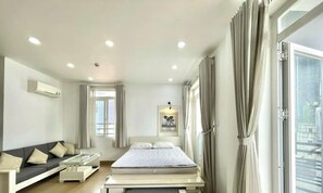 Een moderne hotelkamer met een bed, een bank, een kleine tafel en een raam met gordijnen.