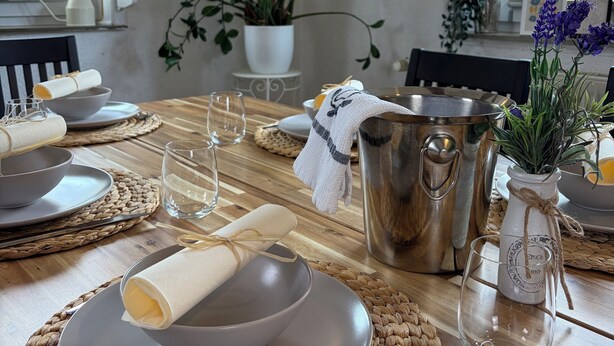 A dining area with a wooden table set for two, a metal pot, and potted plants. - Holiday Living Zennern - near Fritzlar & Edersee (Wabern)