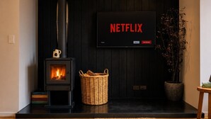 Ett modernt vardagsrum med en vedkamin, en platt-TV som är monterad på väggen och en korg av rotting på golvet.