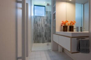 A modern bathroom with a glass shower enclosure, a vanity with a mirror, and a towel rack. - Stackbrae House with Mountain Views (Wānaka)