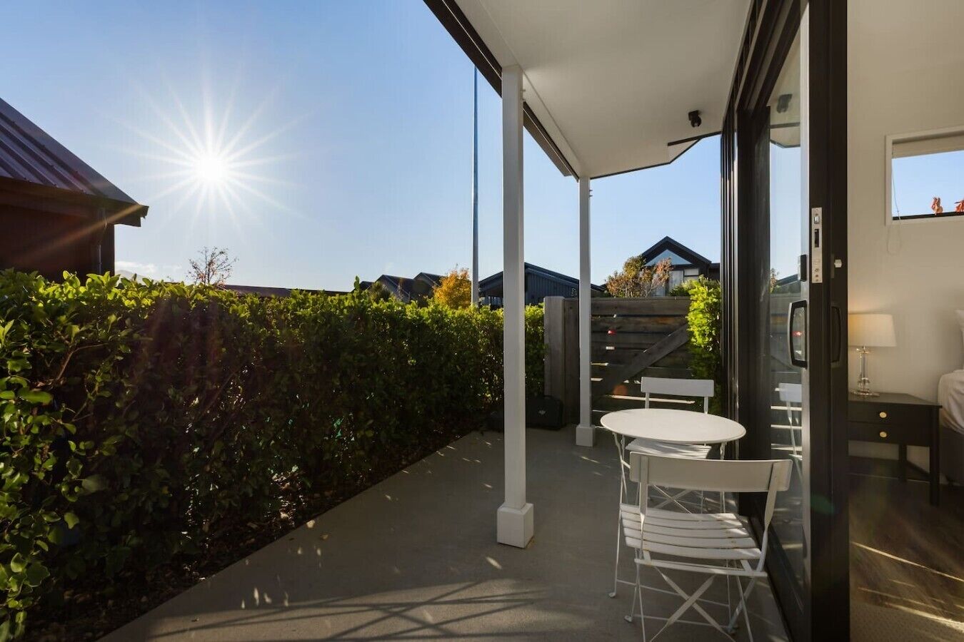 A modern outdoor patio with a table and chairs, a wooden fence, and a view of the surrounding area.