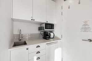 Eine Küche mit Mikrowelle, Kaffeemaschine und Spüle.