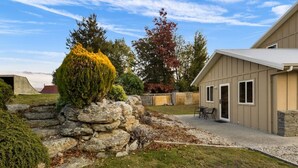 Un immobile residenziale con un muro di sostegno in pietra, un prato ben curato e una casa con garage e area patio.