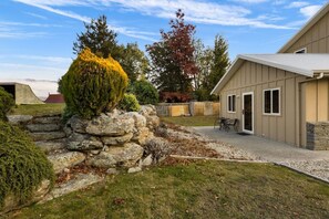 Ein Wohnhaus mit Steinmauer, gepflegtem Rasen, Garage und einer Terrassenfläche.