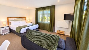 A hotel room with a bed, bedside table, lamp, and a television.