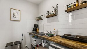 Una cucina moderna con piastrelle bianche a metrò, un piano di lavoro in legno, elettrodomestici in acciaio inossidabile e un quadro appeso al muro.