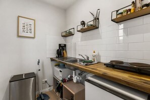Eine moderne Küche mit weißen U-Bahn-Fliesen, einer Holzarbeitsplatte, Edelstahlgeräten und einem gerahmten Bild an der Wand.