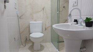 Ein Badezimmer mit Toilette, einer Duschkabine aus Glas und einem Waschbecken mit Topfpflanze.