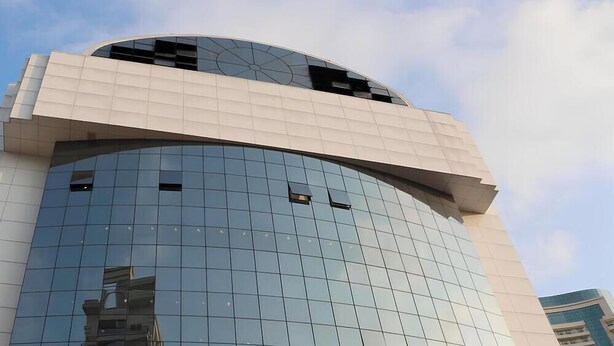 A modern building with a curved glass facade and a flat roof section. - Charmoso na Vila Madalena com AC  (São Paulo)