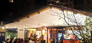 Um restaurante com área de estar coberta ao ar livre, entrada visível e uma placa com caracteres chineses.