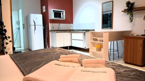 Ein kleines Hotelzimmer mit Bett, einer Küchenzeile, einem Bäder und einem Spiegel.