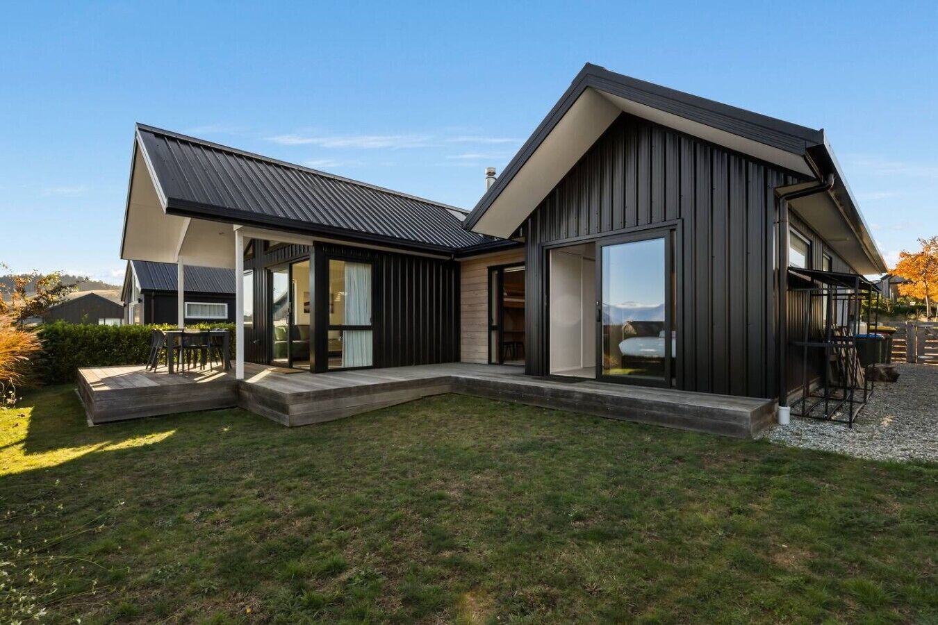 Et moderne hus i to etager med en stor terrasse, skydedøre og udsigt over det omkringliggende landskab.