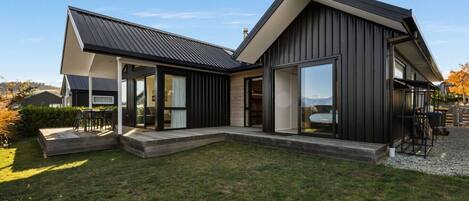 Et moderne hus i to etager med en stor terrasse, skydedøre og udsigt over det omkringliggende landskab.
