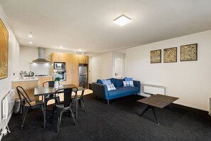 Een knus woongedeelte met een kitchenette, een eethoek, een bank en een kleine tafel.