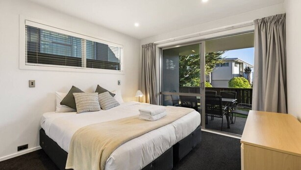 A hotel room with a bed, a desk, a chair, and a view of the outside. - Lake & Alps on Your Doorstep | Resort Facilities (Wānaka)
