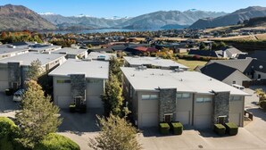 A residential area with modern houses, a parking lot, and a mountainous backdrop. - Lake & Alps on Your Doorstep | Resort Facilities (Wānaka)