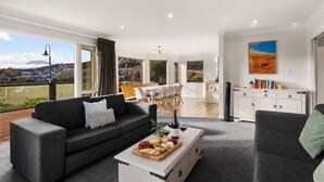Ein modernes Wohnzimmer mit einer Couch, einem Couchtisch mit Snacks und Blick auf einen Essbereich.