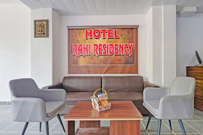 A hotel lobby with a brown sofa, two armchairs, a wooden coffee table with a snack basket, and a large sign reading 'HOTEL RAHI RESIDENCY'. - Hotel Rahi Residency (Varanasi)