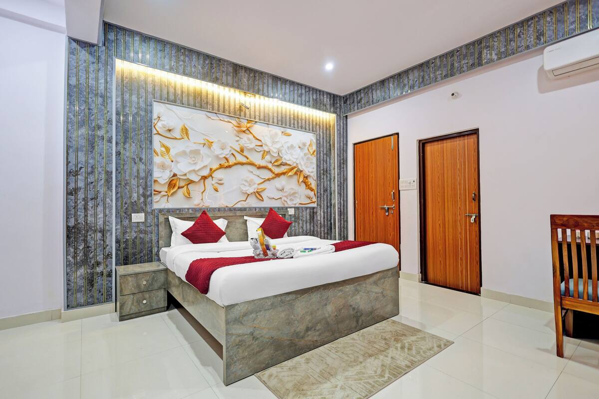 A modern bedroom with a large bed, a decorative wall panel, a wooden door, and a chair.