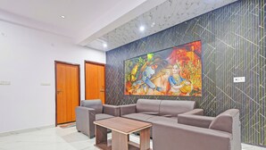 A modern lobby with a sectional sofa, a wooden coffee table, and a large mural on the wall. - Hotel Rahi Residency (Varanasi)