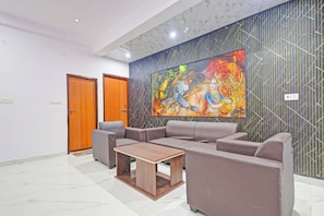 A modern lobby with a sectional sofa, a wooden coffee table, and a large mural on the wall. - Hotel Rahi Residency (Varanasi)