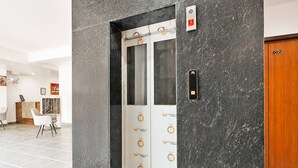 An elevator with a control panel, a reception desk, and a wooden door with the number 002. - Hotel Rahi Residency (Varanasi)