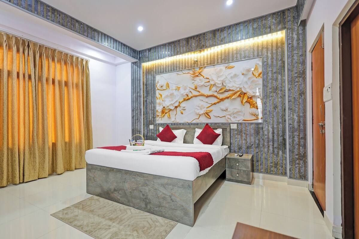 A modern bedroom with a large bed, a nightstand, a wall-mounted artwork, and a curtain.