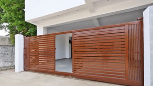 A modern house with a large wooden gate, a concrete driveway, and a white exterior wall. - Hotel Rahi Residency (Varanasi)