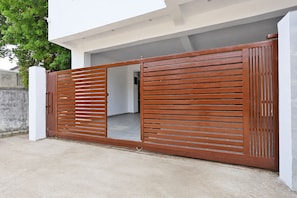 A modern house with a large wooden gate, a concrete driveway, and a white exterior wall. - Hotel Rahi Residency (Varanasi)