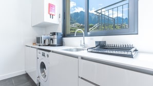 A modern kitchen with a built-in washing machine, a sink, and a window with a view of mountains. - Casa Barranca by Atlantic Holiday (São Vicente)