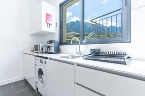 Eine moderne Küche mit Einbauwaschmaschine, Spüle und Fenster mit Bergblick.