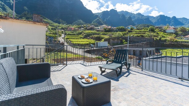 A terrace with outdoor furniture, a table with plates and glasses, and a view of a mountainous landscape. - Casa Barranca by Atlantic Holiday (São Vicente)
