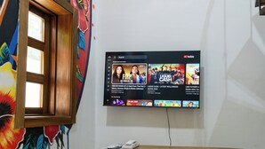 A room with a wooden TV stand, a round wooden coffee table, and a colorful wall mural. - Lobster Beach Resort (Lekki)