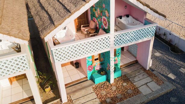 A beachside building with a thatched roof, a jacuzzi, and a colorful interior. - Lobster Beach Resort (Lekki)