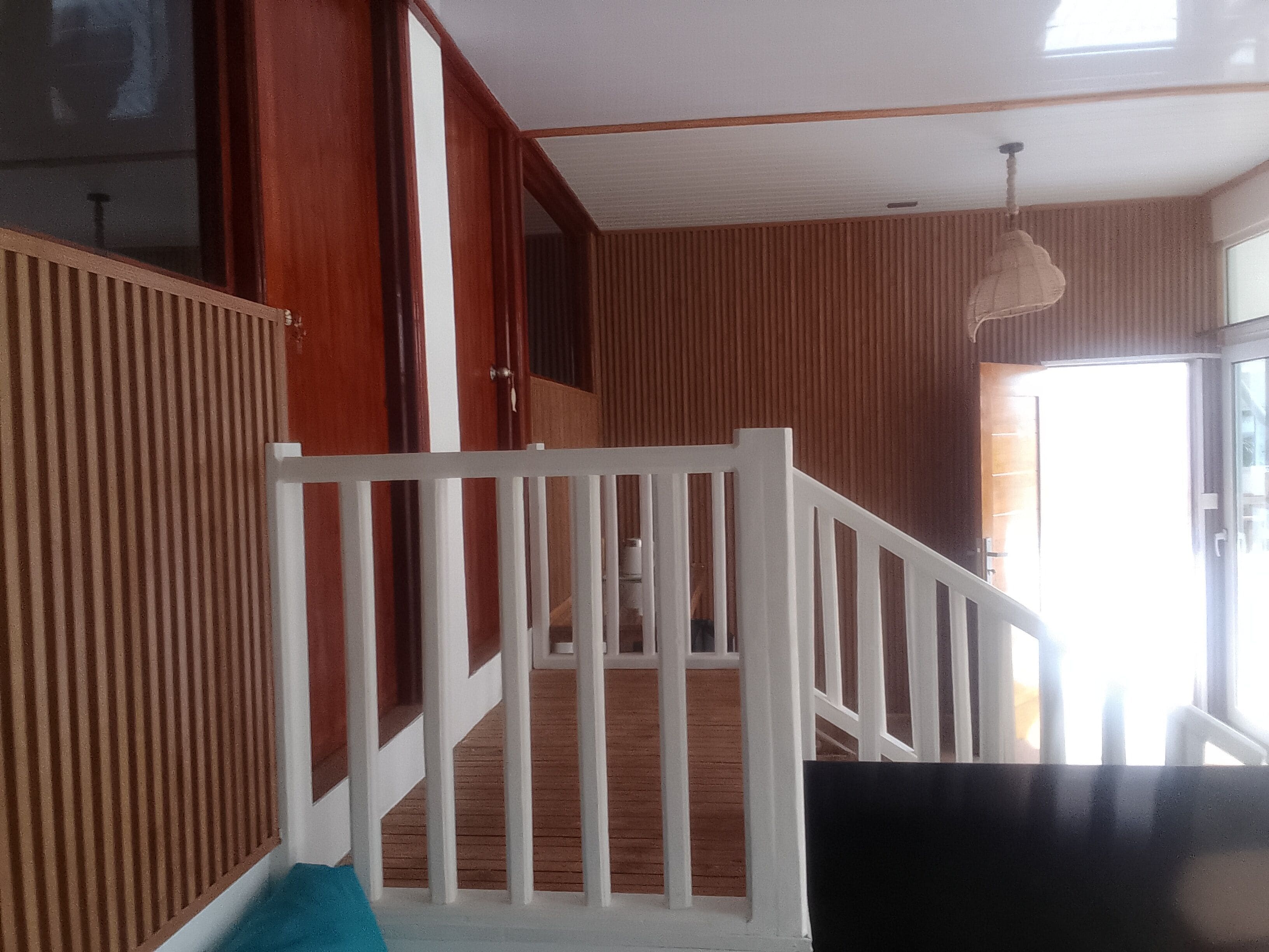 Eine Treppe mit weißer Geländer, Holzwänden und einer Deckenleuchte.