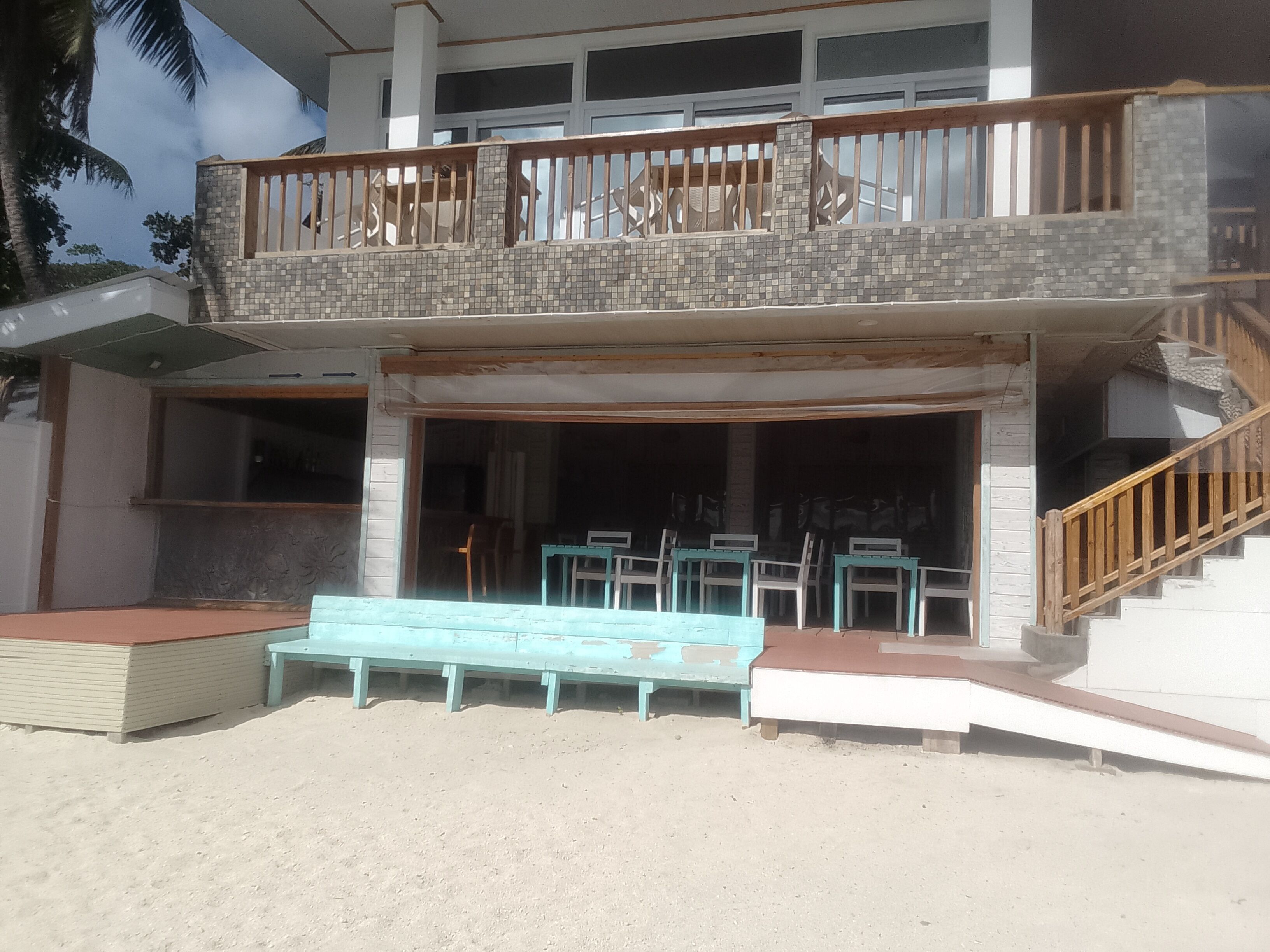 A two-story building with a balcony, a staircase, and a seating area with chairs.