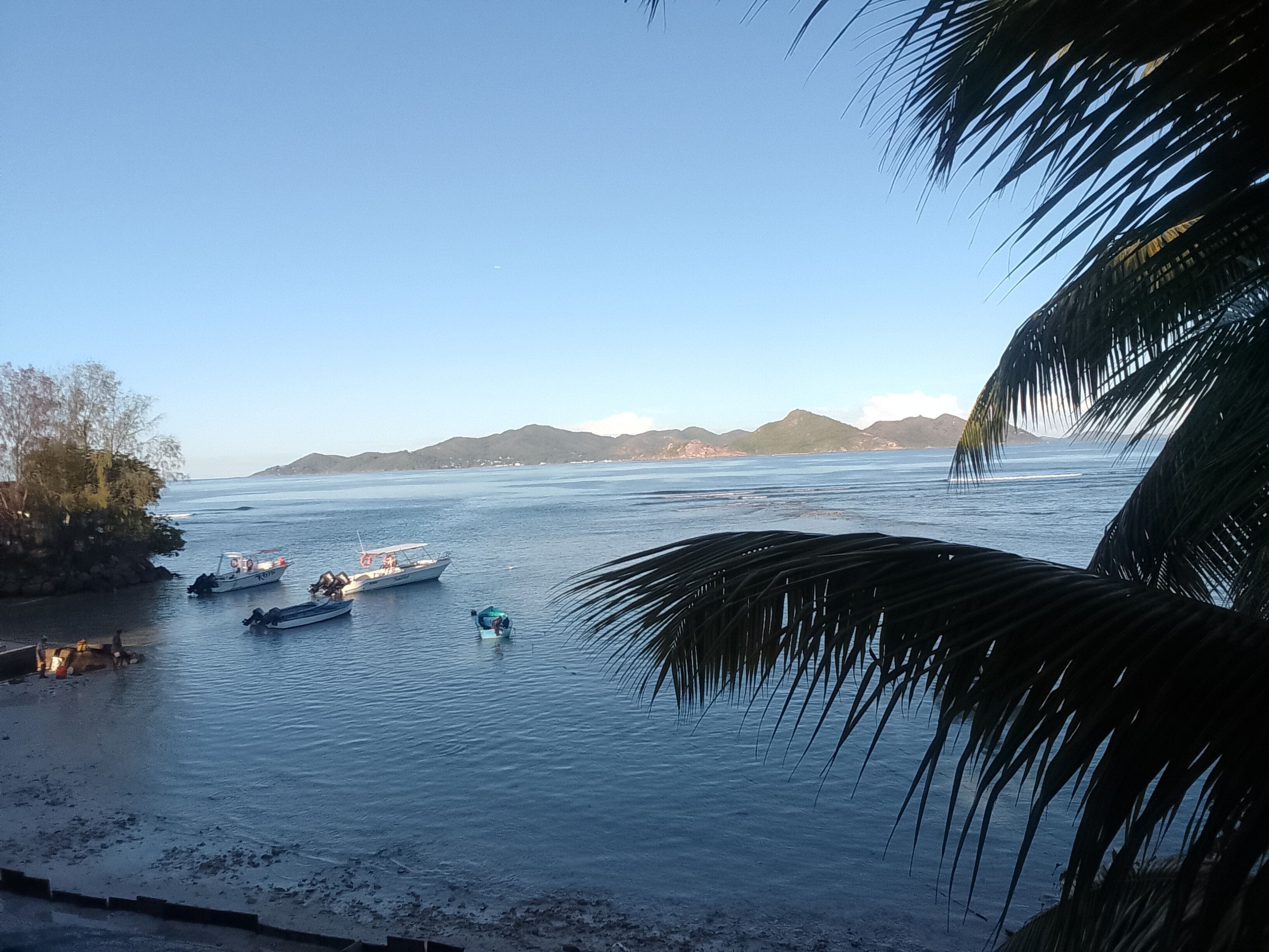 A calm body of water with boats and a distant shoreline.