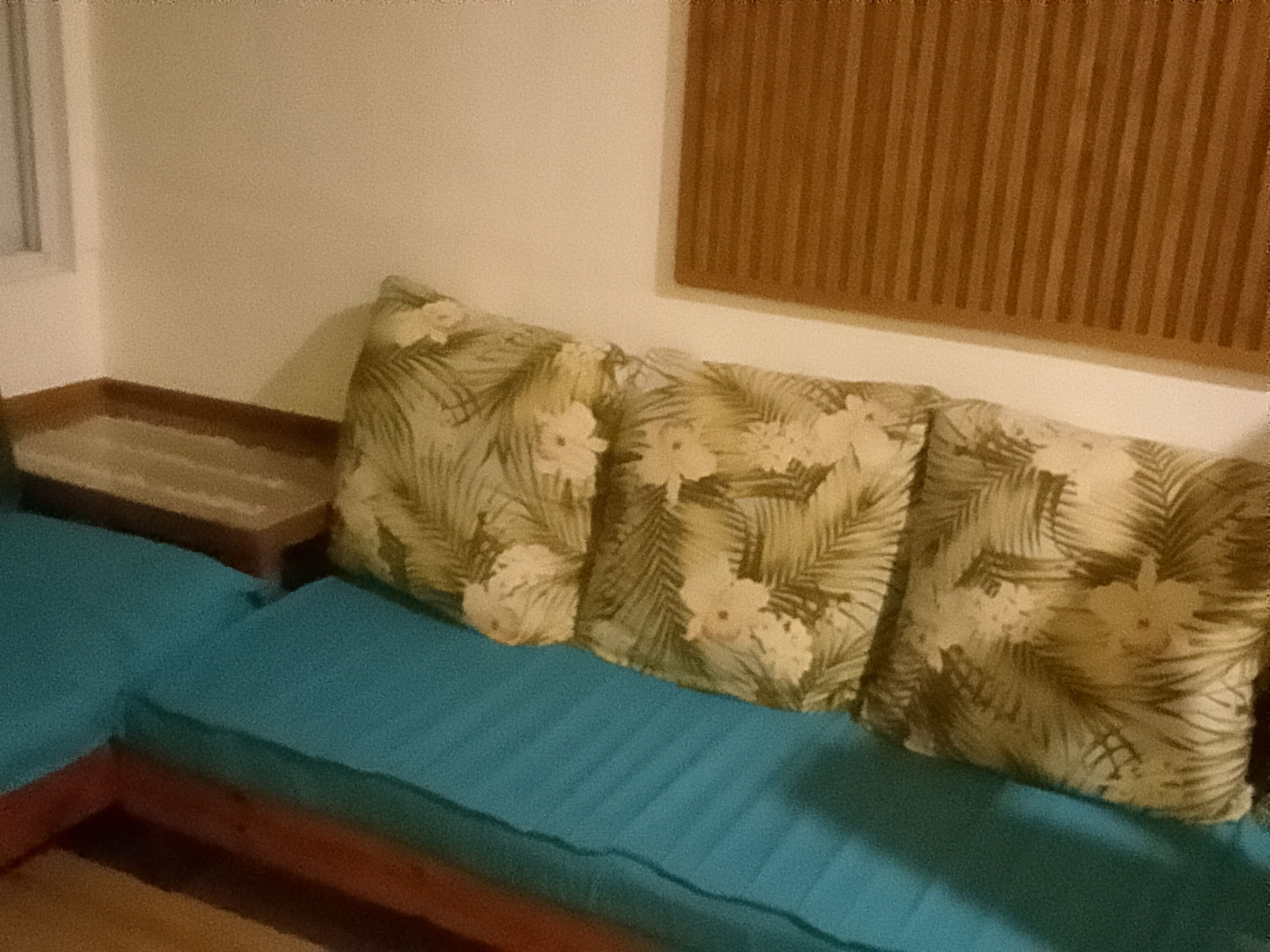 Una habitación con un sofá, una mesita de madera y una ventana con persianas.